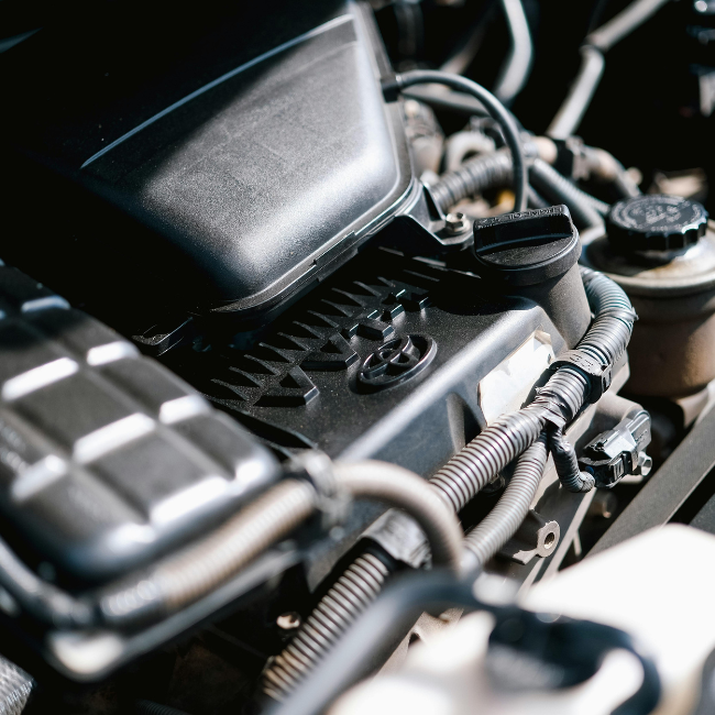 Close-up view of a car engine, highlighting various components, wires, and hoses under the hood—ideal for illustrating head gasket repair details.